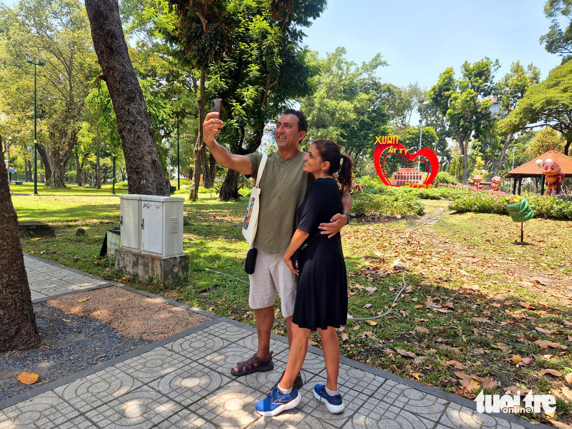 Tej and Pam, a Canadian married couple, happily take photos at Tao Dan Park in District 1, Ho Chi Minh City. Photo: Long Vu / Tuoi Tre