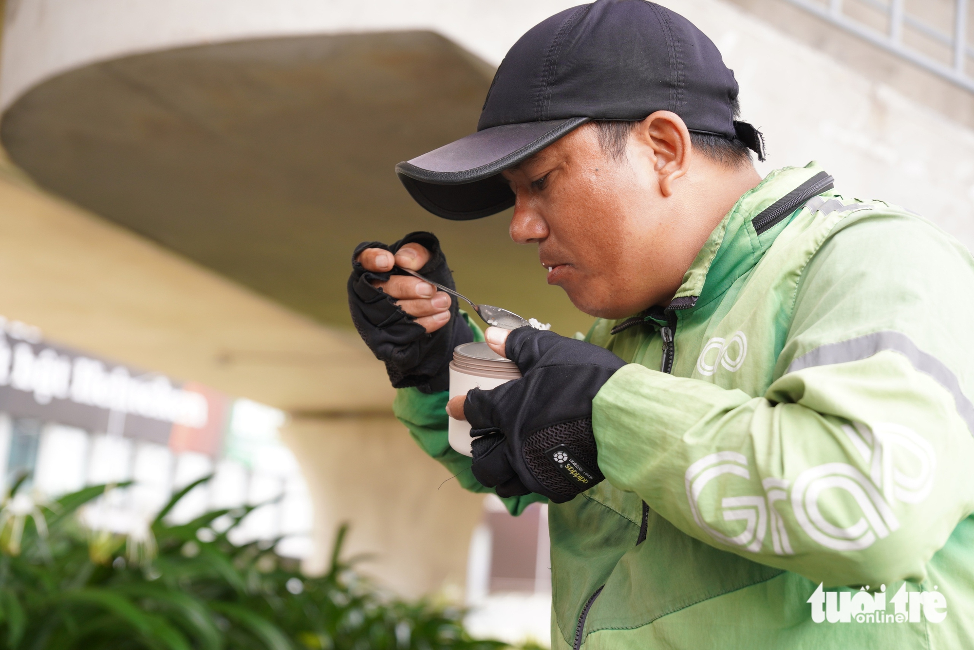 Nguyen Huu Thang, a 39-year-old food delivery driver from Binh Chanh District, Ho Chi Minh City, quickly eats his pre-packed lunch to continue working through midday. Photo: An Vi / Tuoi Tre