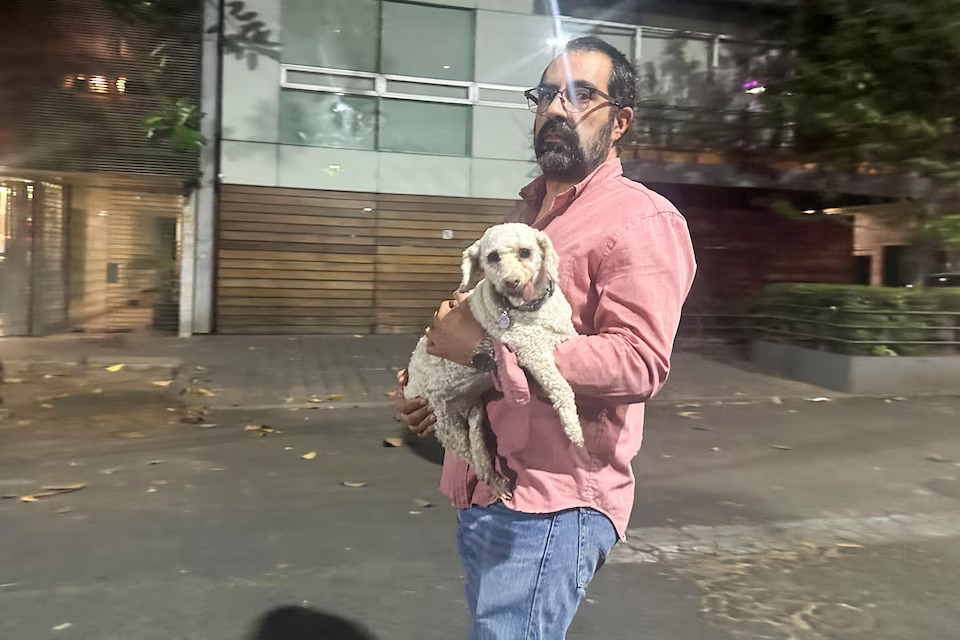 A man holds his dog after an alarm warning of a tremor sounded, in Mexico City, Mexico, March 14, 2025. Photo: Reuters