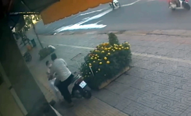 This surveillance camera image captures Bui Chi Binh attempting to flee on his motorcycle from the Mai Kim gold shop in Ba Ria-Vung Tau Province, southern Vietnam, with the shop owner trying to block his path at the front of the vehicle, March 14, 2025.