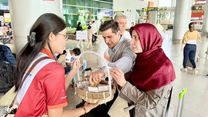 A group of passengers (R) receive gifts from a receptionist after arriving at Tan Son Nhat International Airport in Ho Chi Minh City, Vietnam, March 19, 2025. Photo: Asia DMC