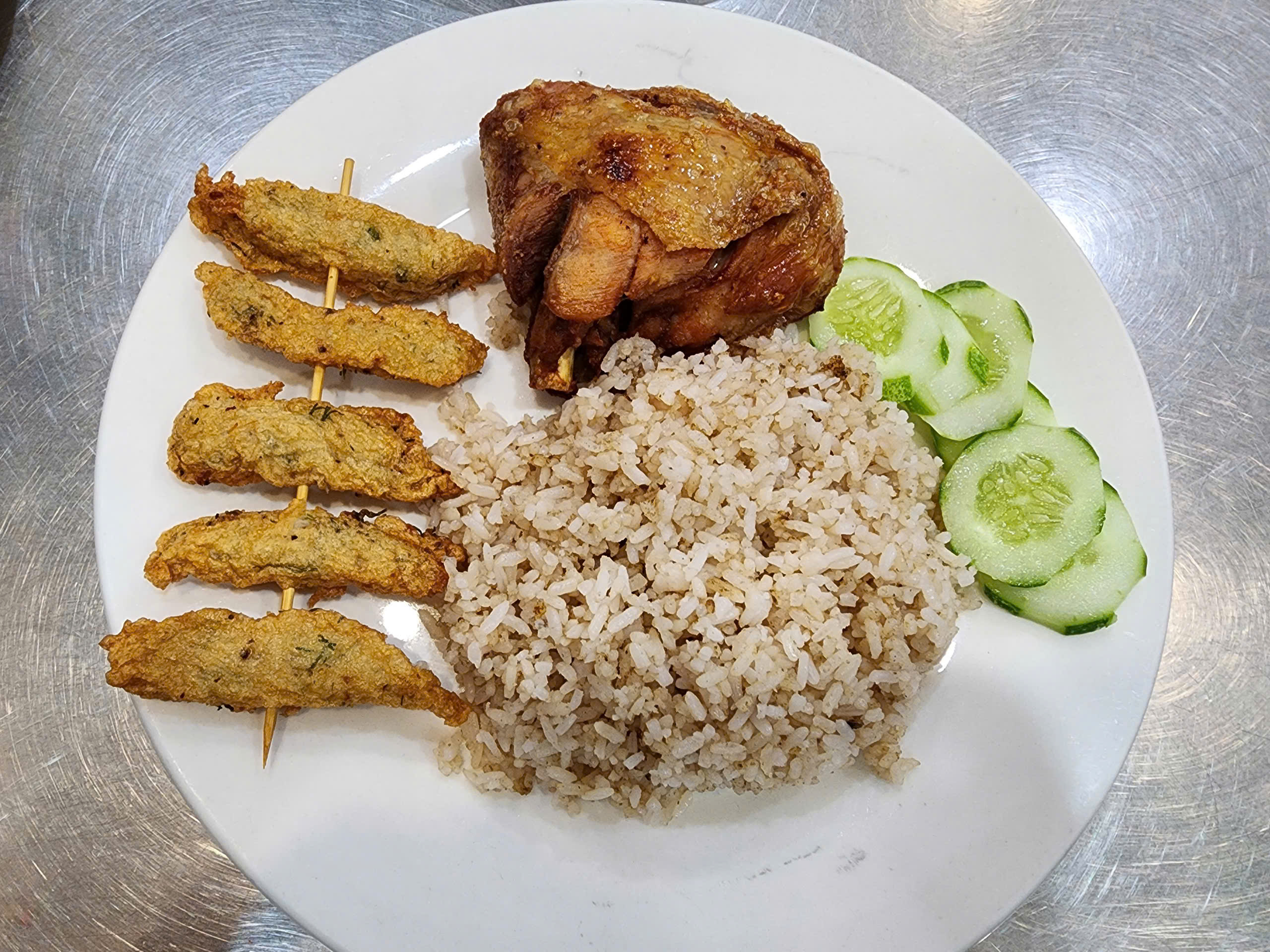 Phat and Hanh’s fried chicken rice is served with an extra skewer of fish cake. Photo: To Cuong / Tuoi Tre