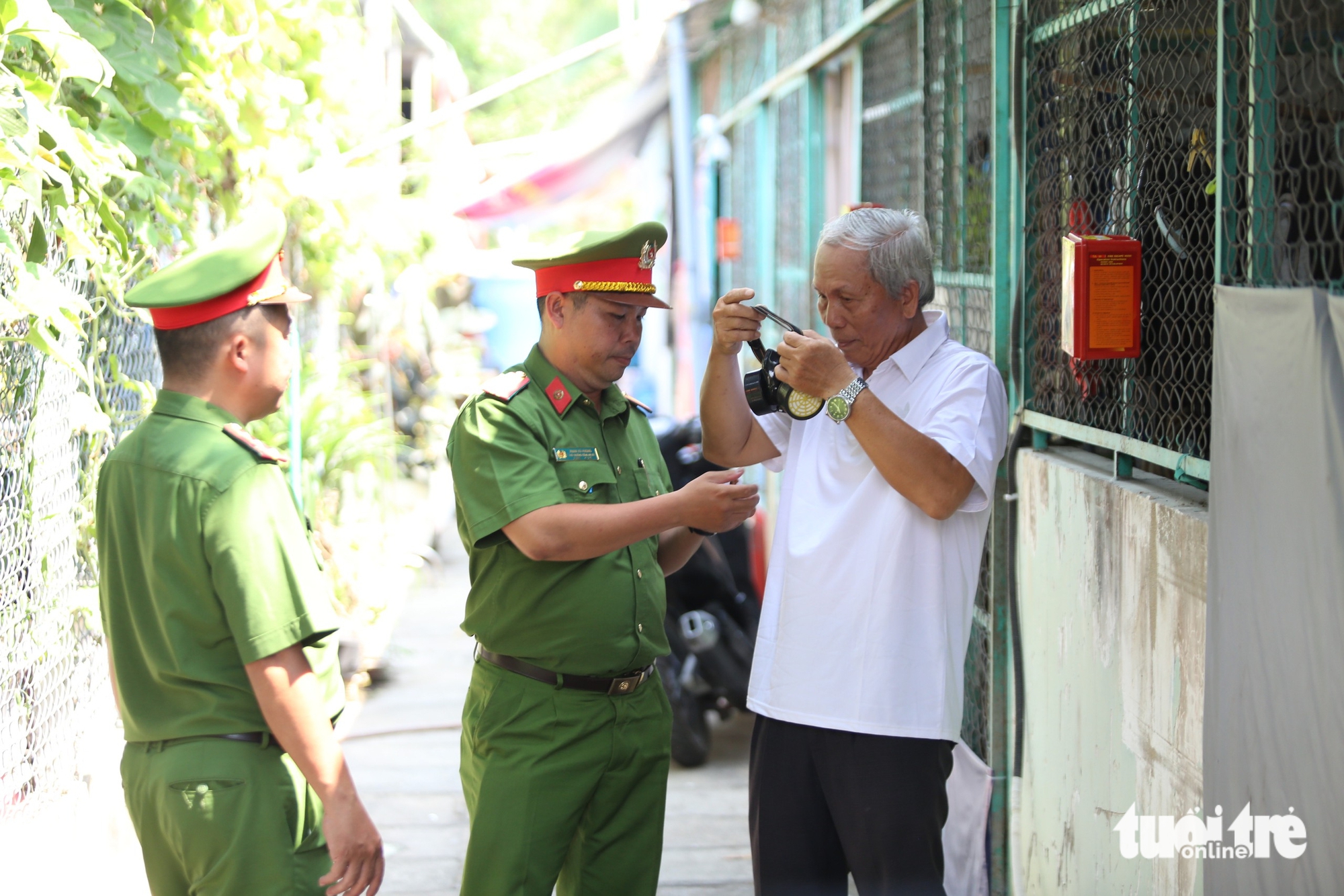 A police officer of Phuoc Kien Commune, Nha Be District, Ho Chi Minh City instructs a boarding house owner how to use a respirator mask, March 21, 2025. Photo: Minh Hoa / Tuoi Tre